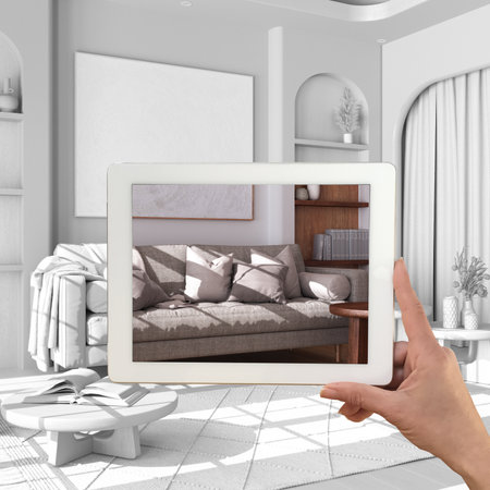 Augmented reality concept. Hand holding tablet with AR application used to simulate furniture products in custom architecture design, total white background, farmhouse living roomの写真素材