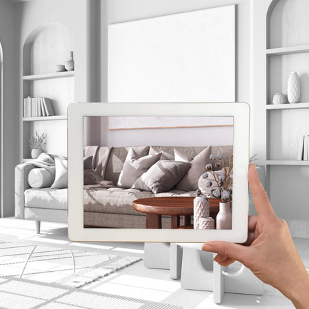 Augmented reality concept. Hand holding tablet with AR application used to simulate furniture products in custom architecture design, total white background, farmhouse living roomの写真素材