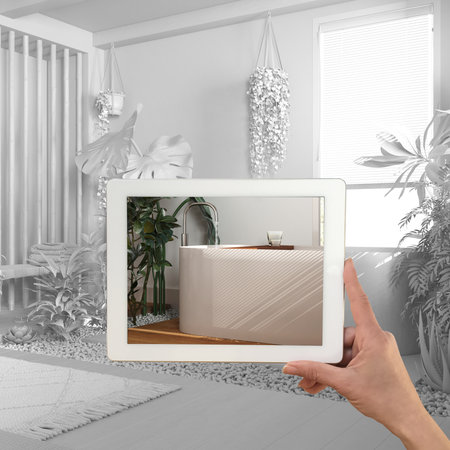 Augmented reality concept. Hand holding tablet with AR application used to simulate furniture and...