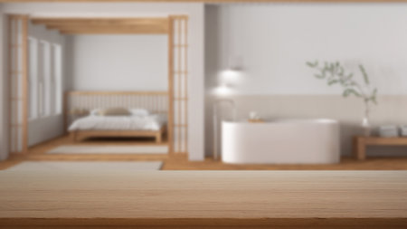 Empty wooden table, desk or shelf with blurred view of bathroom and bedroom in minimal style. Bed and freestanding bathtub, modern interior design conceptの写真素材