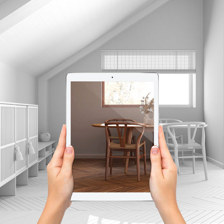 Augmented reality concept. Hand holding tablet with AR application used to simulate furniture and design products in total white unfinished background, japandi minimal dining roomの写真素材