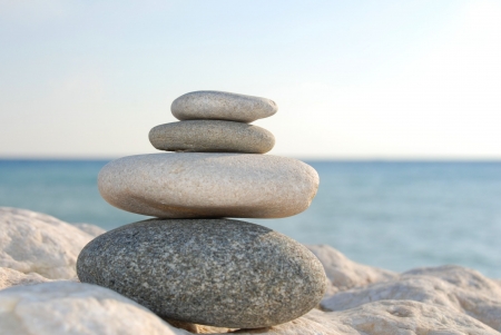 four stones lying upon another in front of the oceanの写真素材