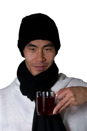 asian man in winter clothes holds an glas in his hand filled with punch or red teaの写真素材