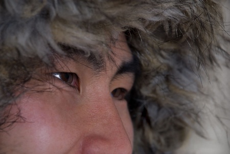 closeup of asian or inuit looking man with coat above his head, in outlineの写真素材