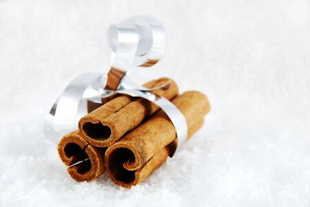 three cinnamon sticks as a present lying in the snowの写真素材