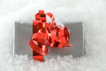 one single silver gift with red bow in the snowの写真素材