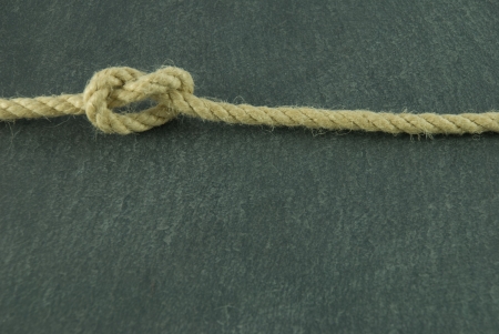 a rope with a knot in it lying on a slate stoneの写真素材