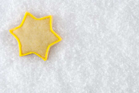 one christmas star cookie lying in the snow, with copyspaceの写真素材