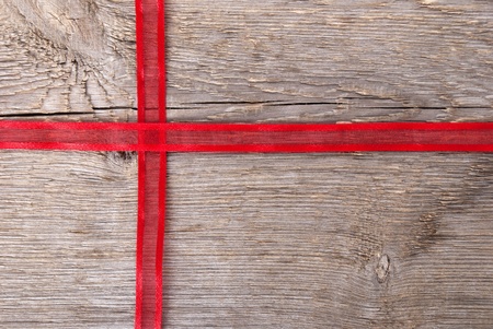 red ribbon on wood in shape of a cross with copy space as backgroundの写真素材