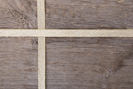 golden ribbon in form of a cross on wood as gift backgroundの写真素材
