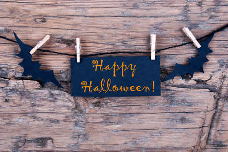 Orange Happy Halloween on a Black Label on a Line with Bats on Woodの写真素材