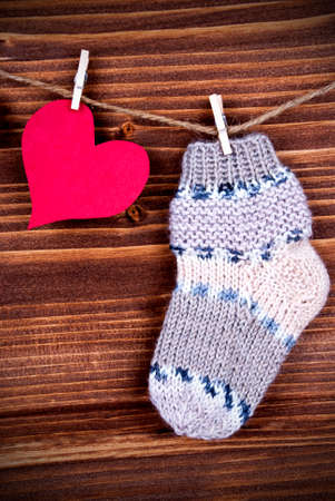 Baby Stocking Hanging on a Line together with a red Heart, on Wood