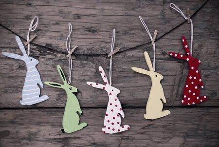 Five Colorful Easter Bunnies Hanging On A Line Which Are Dotted And Striped On Brown Wooden Vintage...
