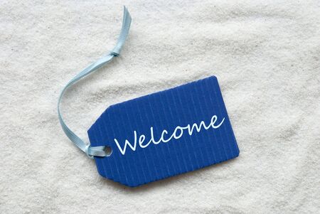 One Blue Label Or Tag With Light Blue Ribbon On White Sand Background With English Text Welcomeの写真素材