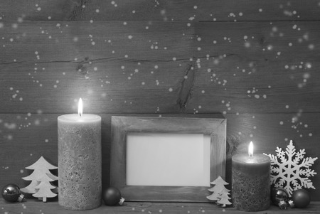 Christmas Decoration With Candles, Christmas Tree, Christmas Ball, Snowflakes. Empty Picture Frame For Copy Space. Peaceful Atmosphere With Candlelight. Wooden Background. Black And White Imageの写真素材