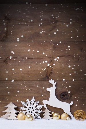 Vertical Christmas Card With White And Golden Christmas Decoration On Snow. Copy Space For Advertisement. Decoration Like Snowflakes, Balls, Tree And Reindeer. Vintage, Rustic Wooden Background.の写真素材