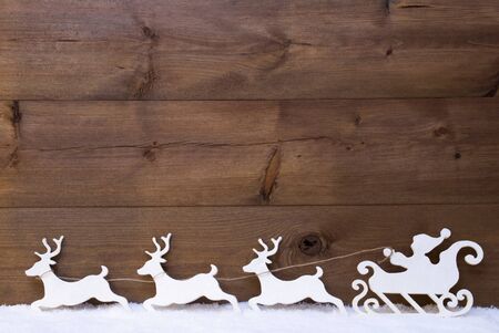 Christmas Decoration, White Santa Claus With Sled And Reindeer On Snow. Brown Vintage Wooden Background With Copy Space. Christmas Card For Seasons Greetingsの写真素材