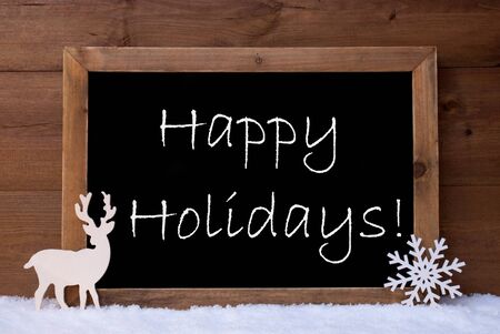 Christmas Card, With Snowflake And Reindeer On White Snow. Brown, Rustic, Vintage Wooden Background.  Christmas Decoration With English Text Happy Holidaysの写真素材