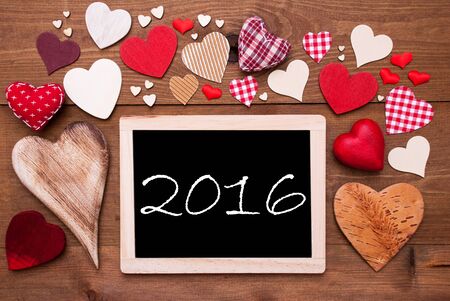 Chalkboard With Text 2016 For Happy New Year Greetings. Many Red Textile Hearts. Wooden Background...