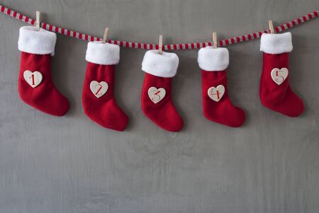 Nicholas Boots As Advent Calendar Hanging On A Line. Cement Wall As Modern Background. Textile Shoes...