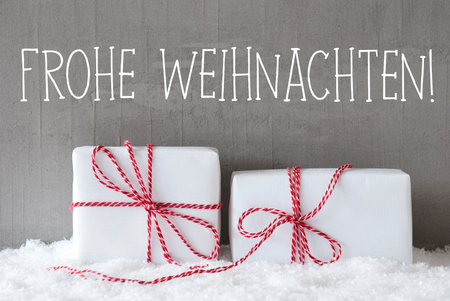 German Text Frohe Weihnachten Means Merry Christmas. Two White Christmas Gifts Or Presents On Snow. Cement Wall As Background. Modern And Urban Style.の写真素材