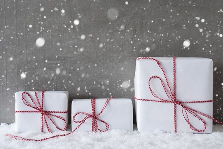 Three Christmas Gifts Or Presents On Snow. Cement Wall As Background With Snowflakes. Modern And Urban Style. Card For Birthday Or Seasons Greetings. Copy Space For Advertisementの写真素材