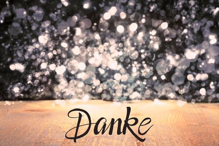 German Calligraphy Danke Means Thank You. Black Christmas Background With Sparkling Lights And Woodの写真素材