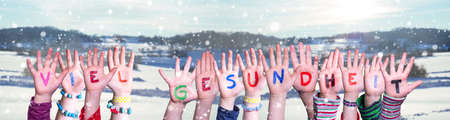 Kids Hands Holding Word Viel Gesundheit Means Stay Healthy, Snowy Winter Backgroundの写真素材