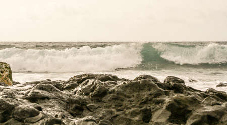 wave view from the beach with rocks to the sea