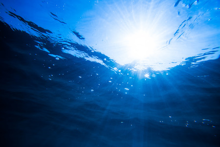 underwater background, deep blue sea with sunraysの写真素材