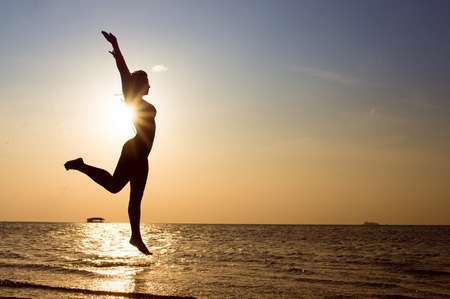 Happy Woman Jumping on the beach. Sea Sunsetの写真素材
