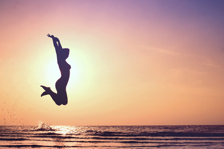Happy Woman Jumping on the beach. Sea Sunsetの写真素材