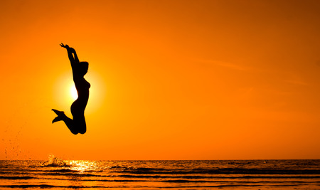 Happy Woman Jumping on the beach. Sea Sunsetの写真素材