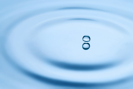 Water drop falling into water making a perfect droplet splash with soft focusの写真素材