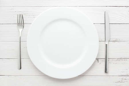 plate, knife and fork on white vintage wooden table backgroundの写真素材