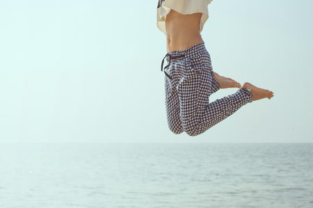 Happy young girl jumping on the beachの写真素材