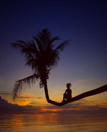 girl on palm tree, silhouette at sunset