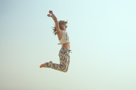 Happy young girl jumping on the beachの写真素材