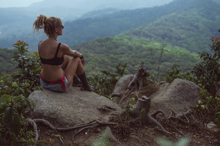 A girl sits on the edge of the cliffの写真素材