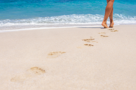 woman legs, walking on the beach. blue sea and skyの写真素材