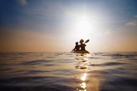 silhouette of people kayaking at sunsetの写真素材