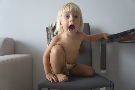 naughty child sitting on a chairの写真素材