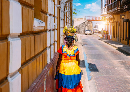 Colombia, lady in national colorful costume walking the streets of Walled City historic center of Cartagena.の写真素材