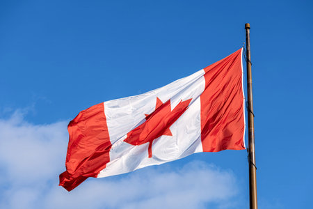 Red and white Canadian flag with a maple leaf waving in the air. Canadian patriotism and cultureの写真素材