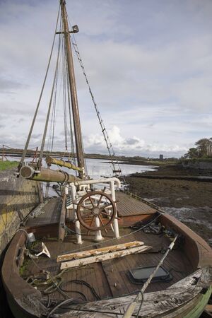 old wooden ship stranded in the port, without sails and with wooden helm, cloudy day