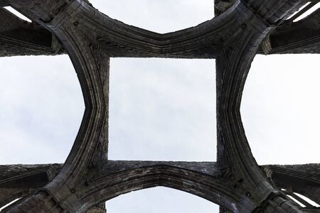 architecture, arches of ancient stone abbey, seen from below, without roofing, you can see the sky