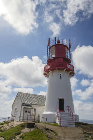 Lighthouse on top of a rock next to a houseの写真素材