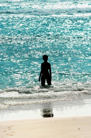 Woman silhouette standig in a shinny warm seaの写真素材