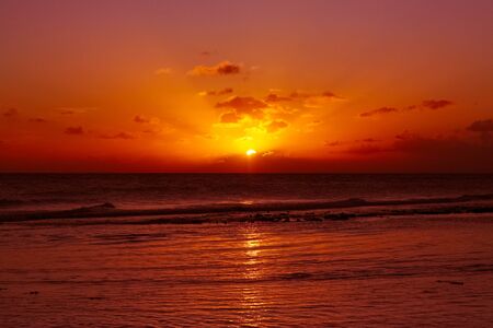 Waves on a red sunset in warm caribbean seaの写真素材