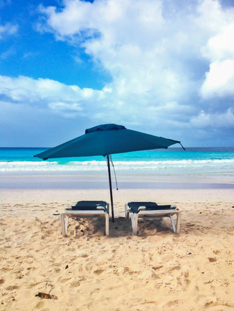 Two lounges with umbrella in tropical beachの写真素材